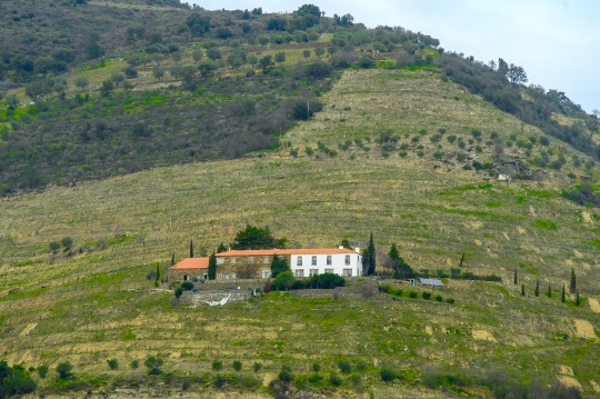 A building in a mountain ridge with agricultural land prepared i