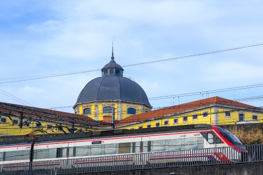 A modern train leaves the railway station, with the old architec