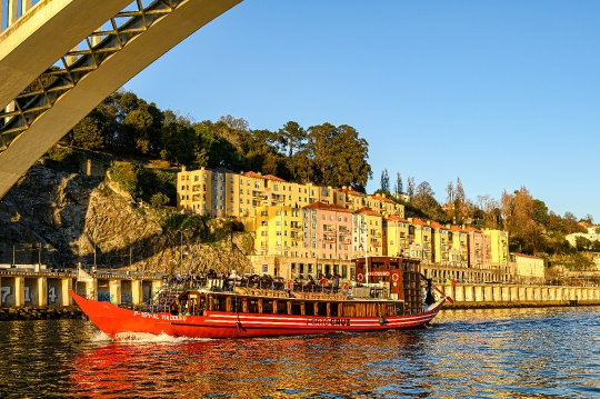 A tour boat moves beneath the Arrabida Bridge on the Douro River