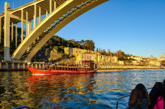 A tour boat moves beneath the Arrabida Bridge on the Douro River