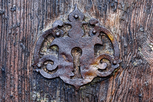 Ancient metallic keyhole on the wooden surface of a medieval doo