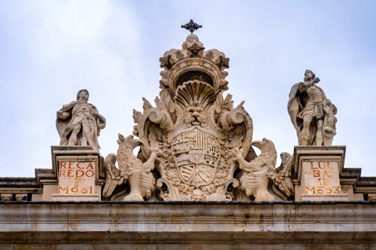 Ancient stone coat of arms and sculptures atop the Royal Palace.