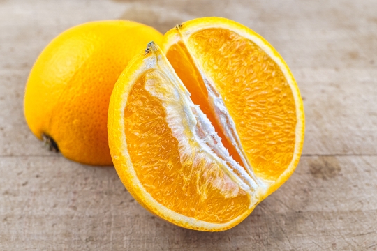 Close-up of an orange fruit on a wooden cutting board.