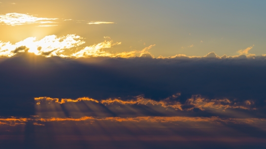 Dawn sunlight beams crossing clouds