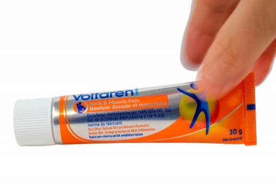 Hand of a woman grabbing a container of Voltaren