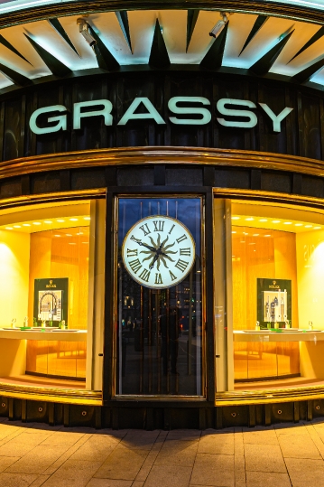 Illuminated windows and a clock in the Grassy building in the Gr