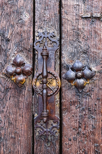 Medieval metallic door handle and rivets on the wooden surface o