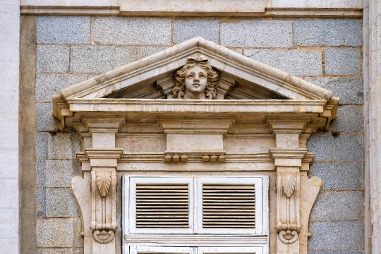 Pediment with a stone sculpture above an exterior window of the 