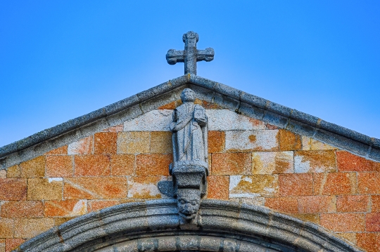 Religious cross and decorative saint statue in the upper section