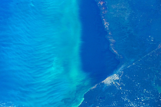 Turquoise and blue sea water by a coastline.