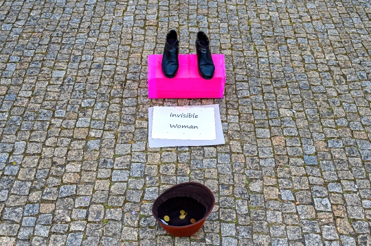 Urban art titled ëInvisible Womaní on a cobblestone street, wi